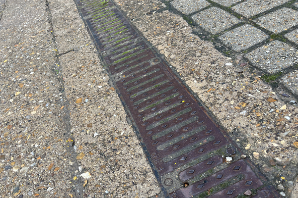 Channel drain and grate badly blocked with silt